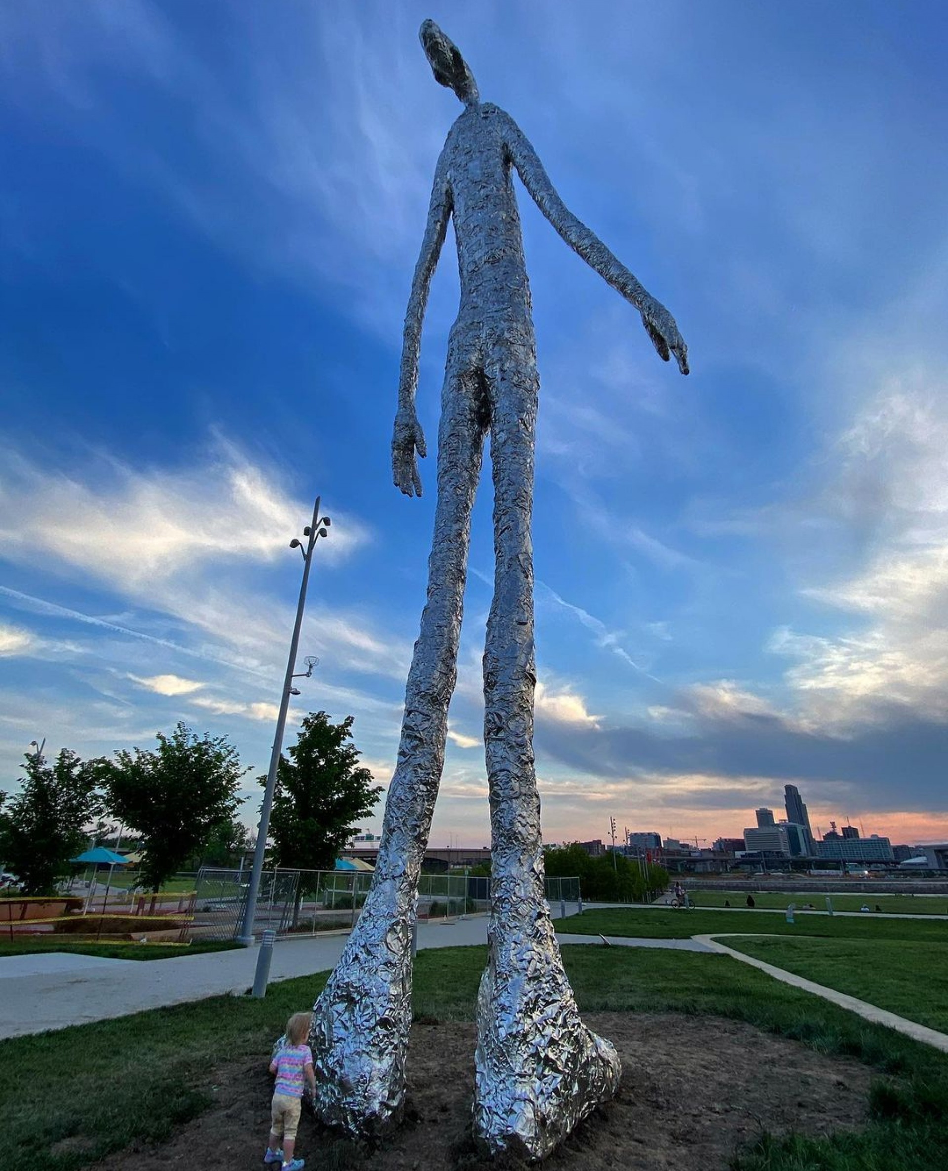 Child standing next to the Looking Up statue in Council Bluffs, Iowa