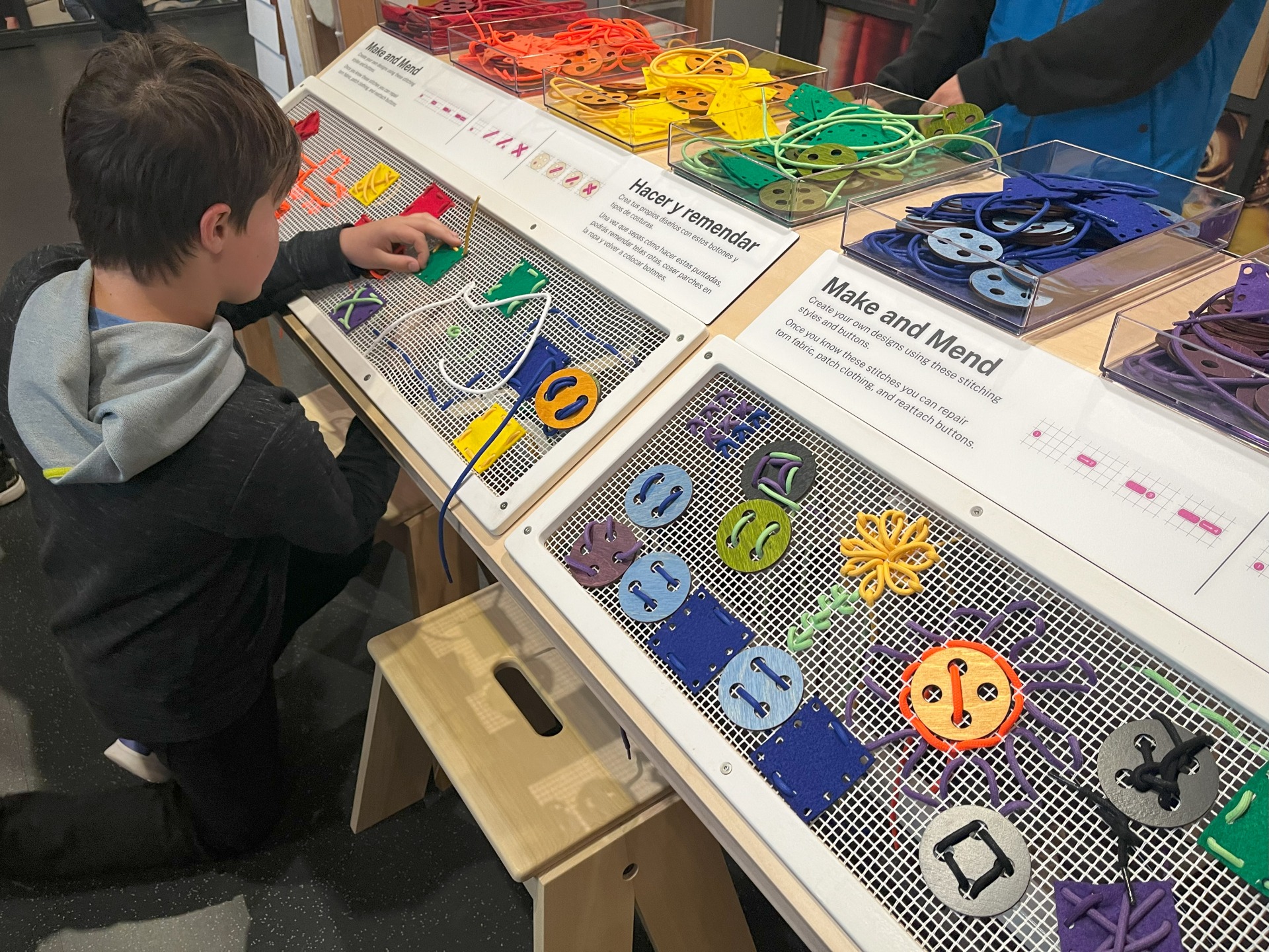 Child playing with the Make and Mend stitching exhibit at the Kiewitt Luminarium