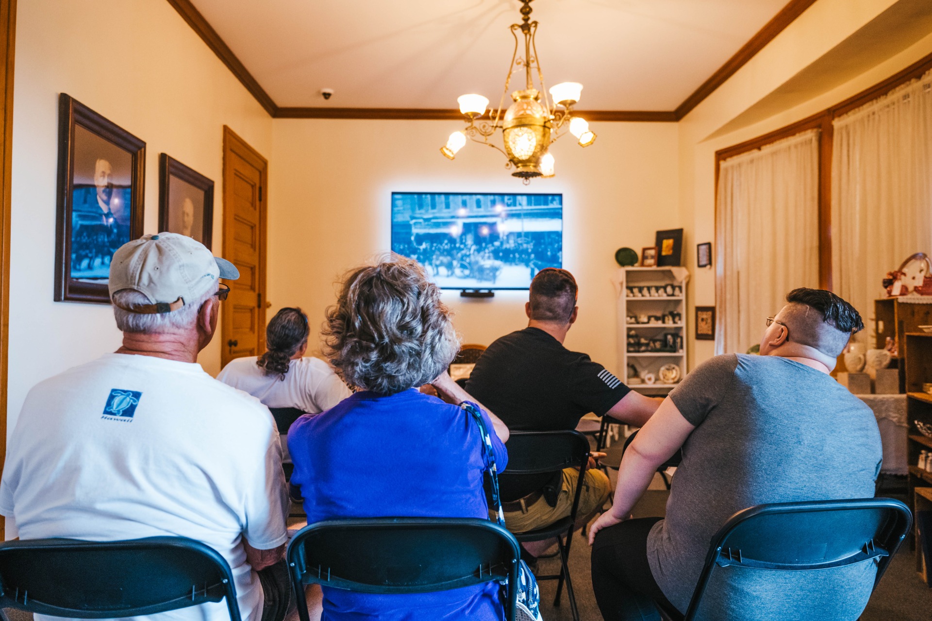Five visitors watching the orientation video at the Historic General Dodge House