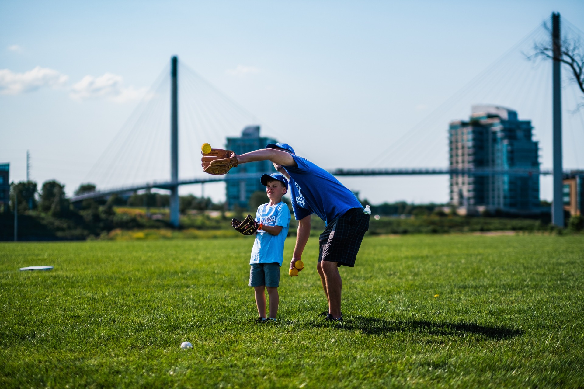 Father and son playing catch in front of the Bob Kerrey Pedestrian Bridge