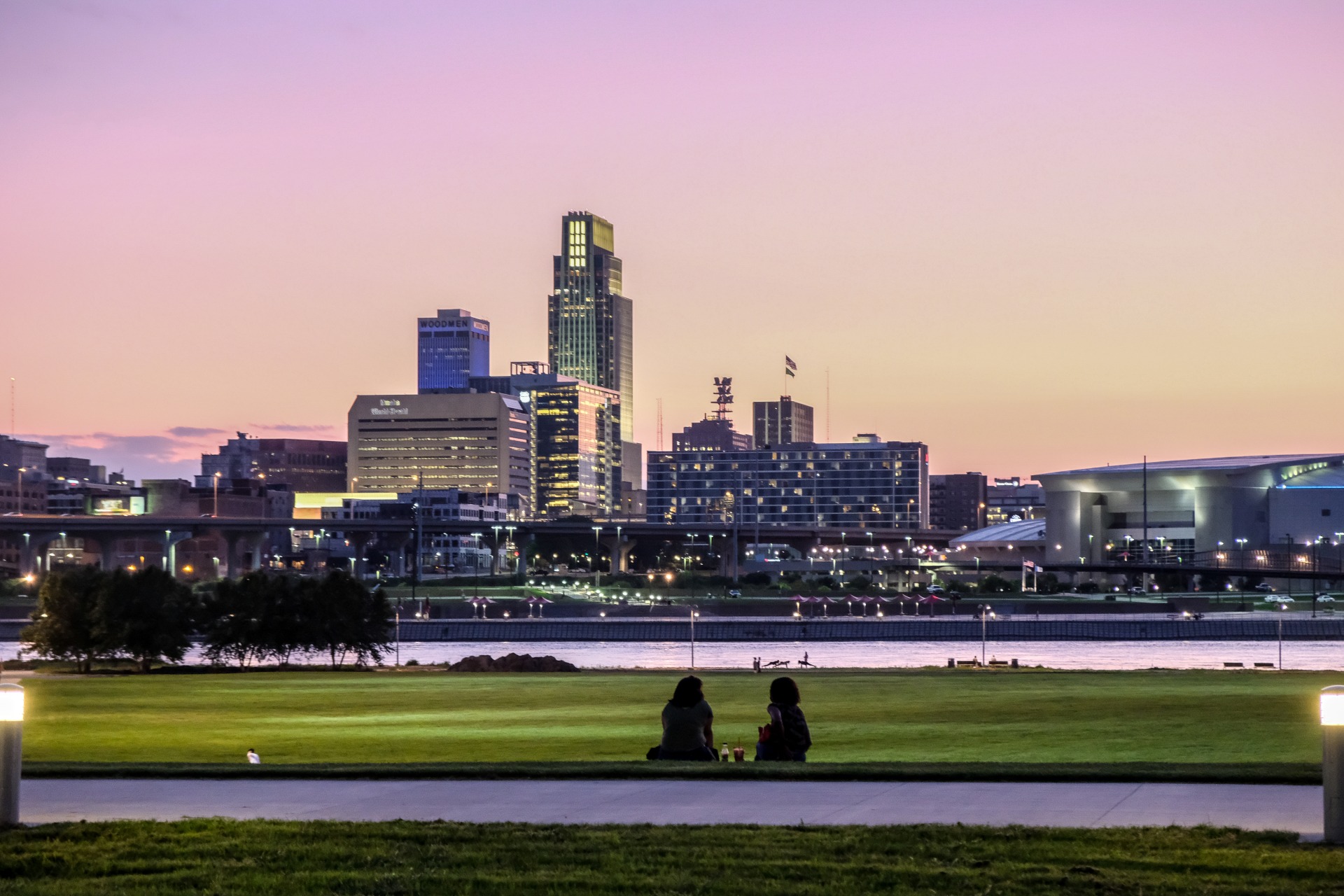 A couple have a picnic with the Omaha skyline in the background