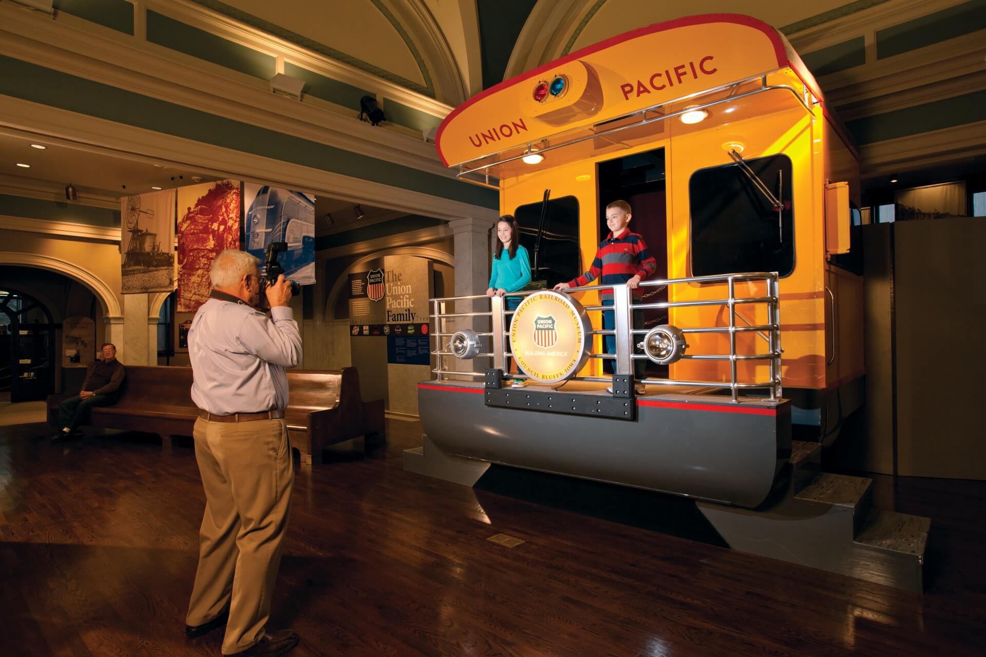 Man taking a photo of two kids on the back of a Union Pacific train car